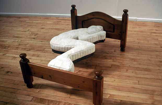 A bed sculpture in the shape of a sleeping person.